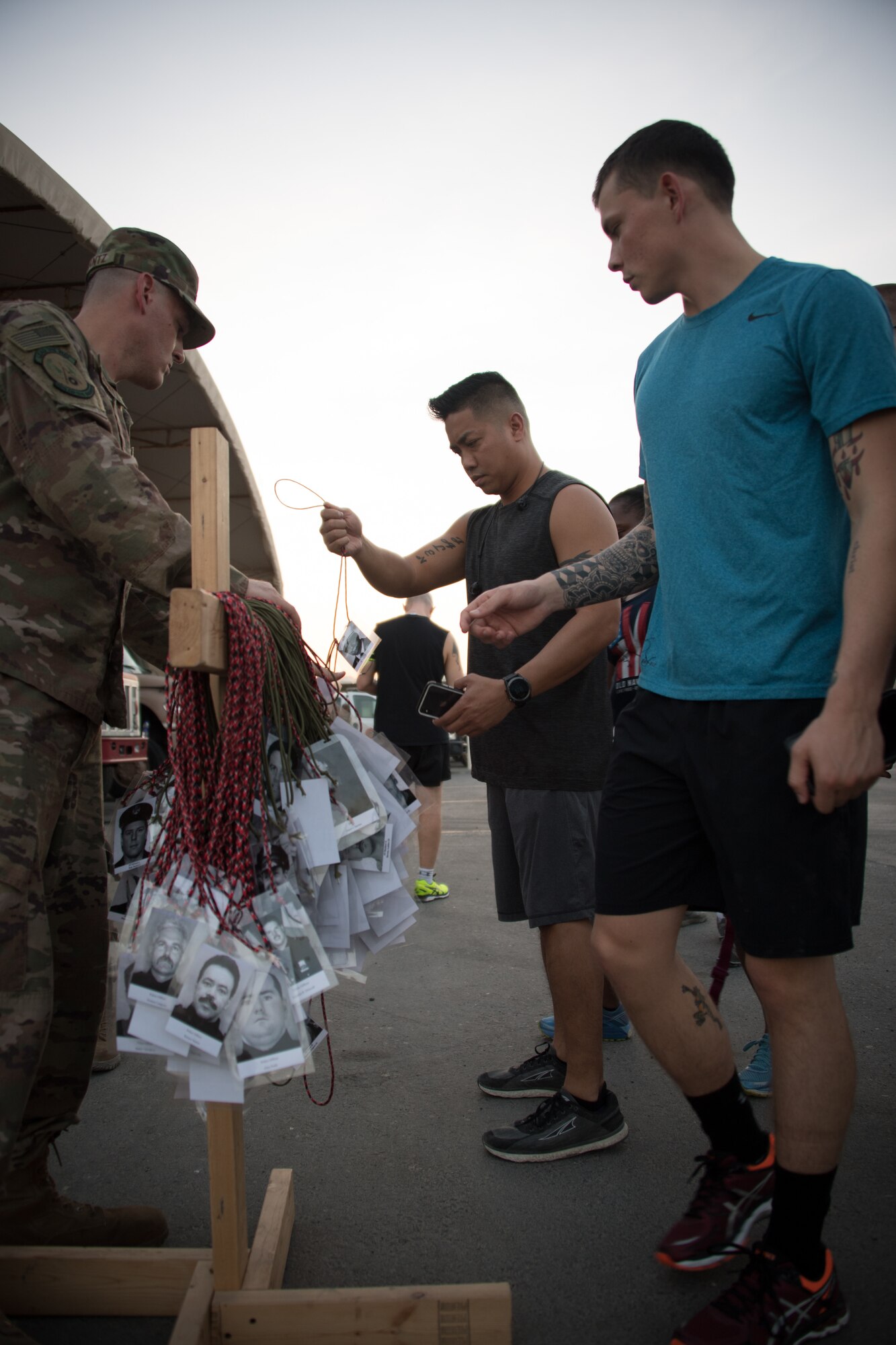 U.S. Airmen from the 380th Air Expeditionary Wing are given lanyards to wear around their neck with the photos of fallen first responders while participating in a memorial 5k run honoring the men and women who gave their lives on 9/11, Al Dhafra Air Base, United Arab Emirates, Sept. 11, 2018. (U.S. Air Force photo by Tech. Sgt. Nieko Carzis)