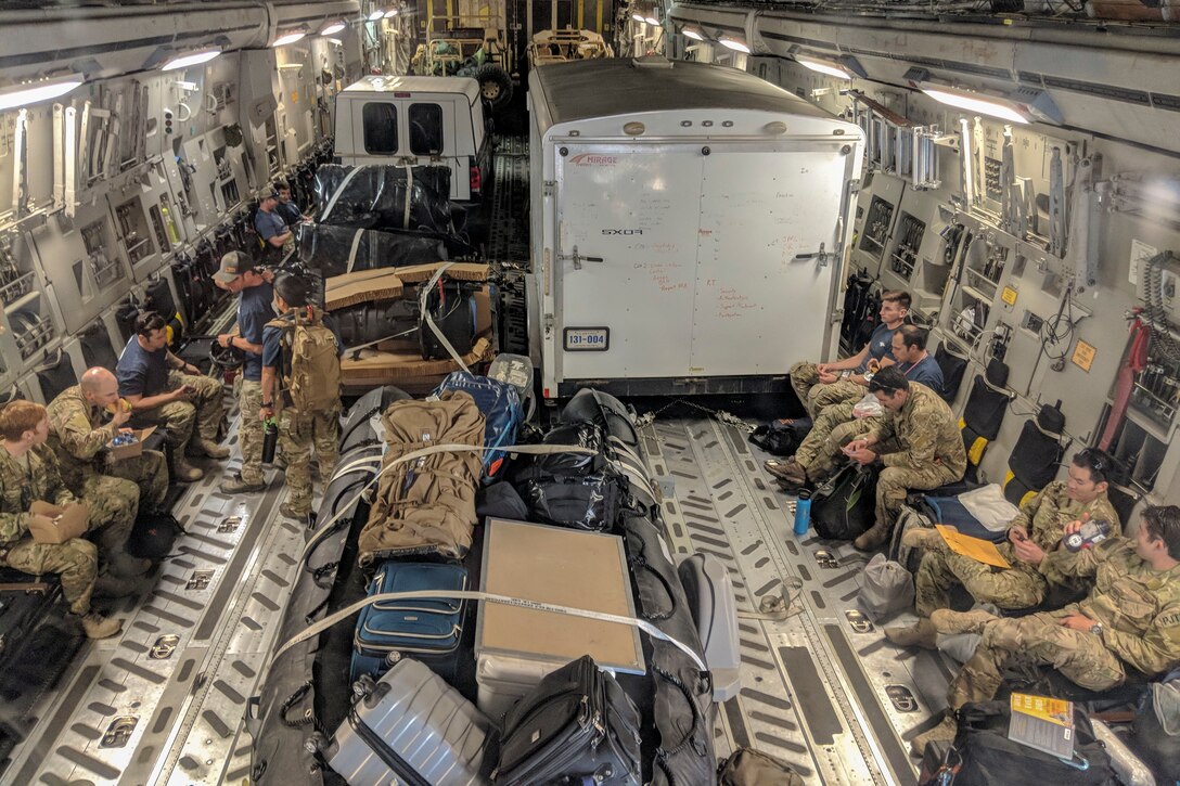 Military personnel sit in a military aircraft.
