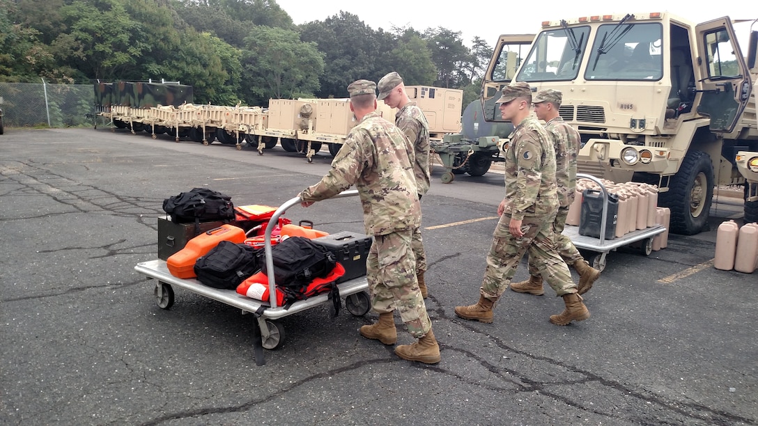 Soldiers push a cart of supplies.