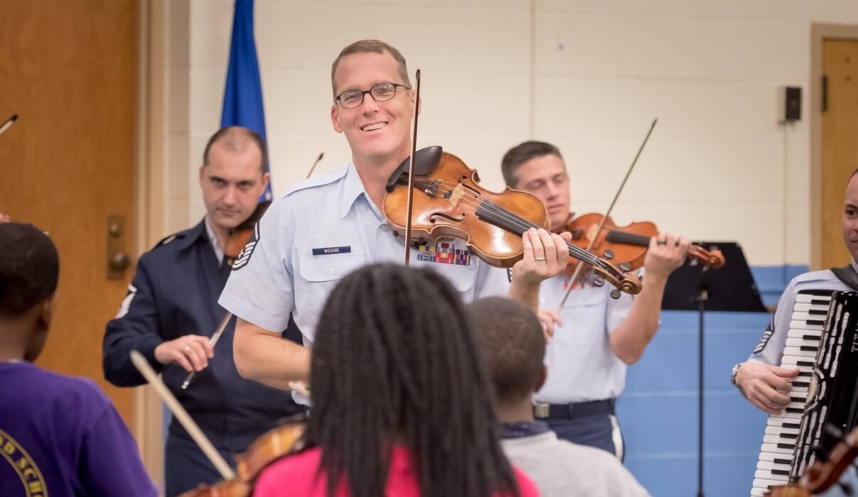 Master Sgt. Luke Wedge performs during a strings clinic at a local school