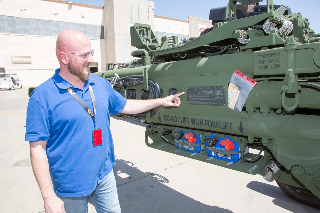 Schyler Yacono, supervisor, TMDE Department, points out the laser engraved information plate created by his artisans in the Graphics Shop aboard PPB, MDMC, Sept. 4. This particular plate is attached to a M777 Howitzer that was refurbished at the plant and details exactly how to attached lines to the huge barrel to transport it by ground or air.