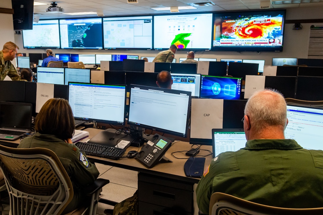 Military personnel sit in front of monitors in an operations center.
