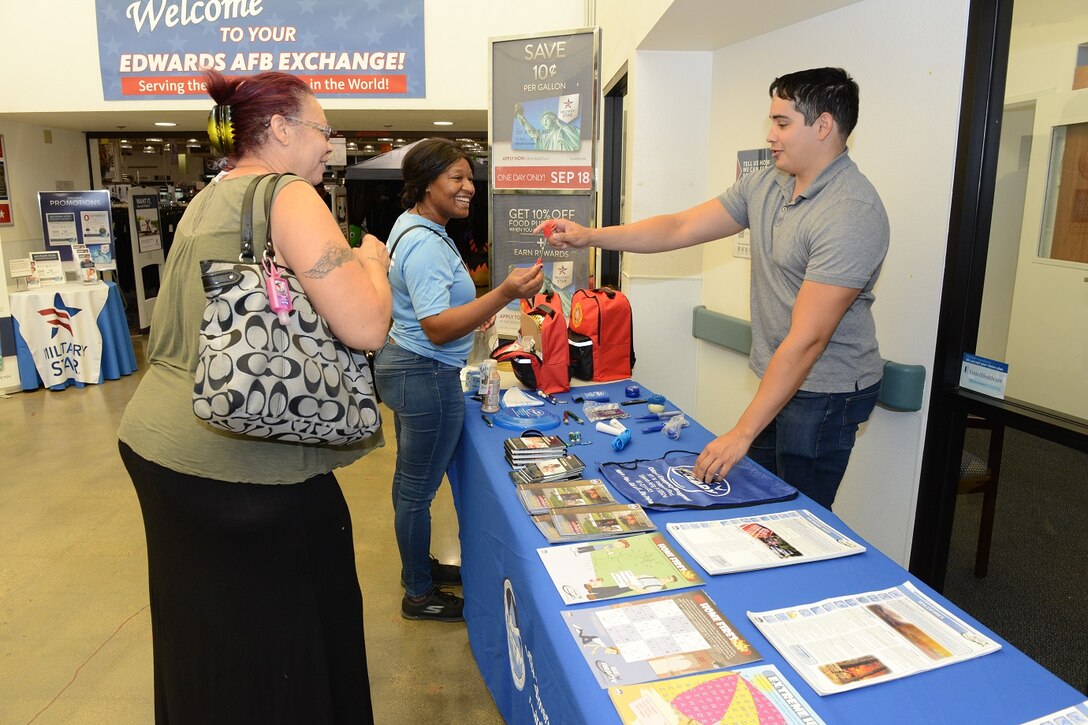 Daven Solis, 812th Civil Engineer Squadron Emergency Management Flight, shows a couple Exchange customers complimentary prizes at an Emergency Management display for National Preparedness Month. Representatives will be on hand at the Exchange 10 a.m. to 2 p.m. from Tuesday-Thursday throughout the month of September. (U.S. Air Force photo by Kenji Thuloweit)