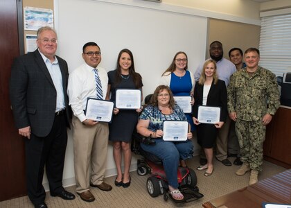 PANAMA CITY, Florida - Naval Surface Warfare Center Panama City Division (NSWC PCD) personnel, who are part of the interdisciplinary Naval Sea Systems Command (NAVSEA) People's Integrated Essential Resource (PIER) team, are recognized with a Special Act Award for their contributions to the NAVSEA Enterprise project Sept. 13, 2018. Pictured from left to right: NSWC PCD Technical Director Ed Stewart (SES), David Galindo, Katherine Mapp, Allison Roberts, Kimberly Ten Broeck, Holly Gardner, Keely Westbrook, Vatana An, and NSWC PCD Commanding Officer Capt. Aaron Peters, USN. U.S. Navy photo by Anthony Powers