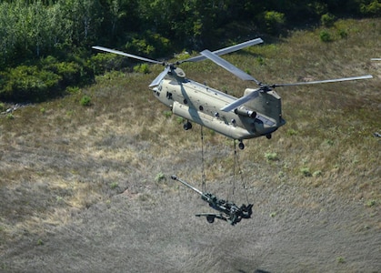 ​A CH-47 Chinook helicopter from 2nd General Support Aviation Battalion, 135th Aviation Regiment, Colorado Army National Guard, airlifts an M777 105mm Howitzer from Camp Grayling, Michigan, to an area in the vicinity of the Combat Readiness Training Center in Alpena, Michigan, Aug. 10, 2018.