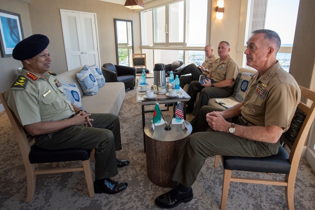 Two defense leaders sit across from each other during a meeting.