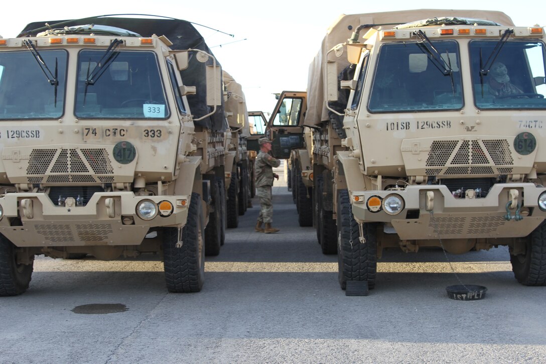 Soldiers with the 101st Airborne Division inspect a line of military vehicles.