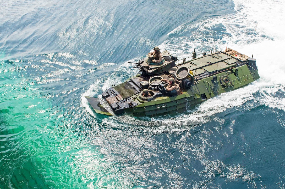 An amphibious assault vehicle travels toward the well deck of a ship.