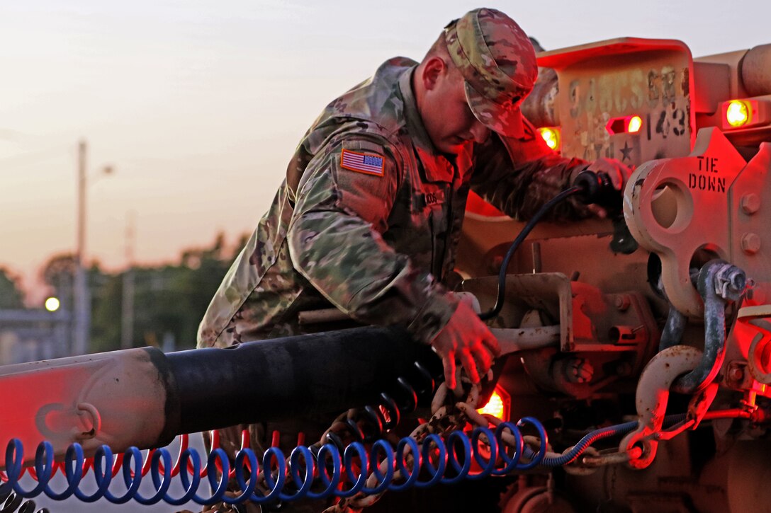 A soldier works on a military truck.