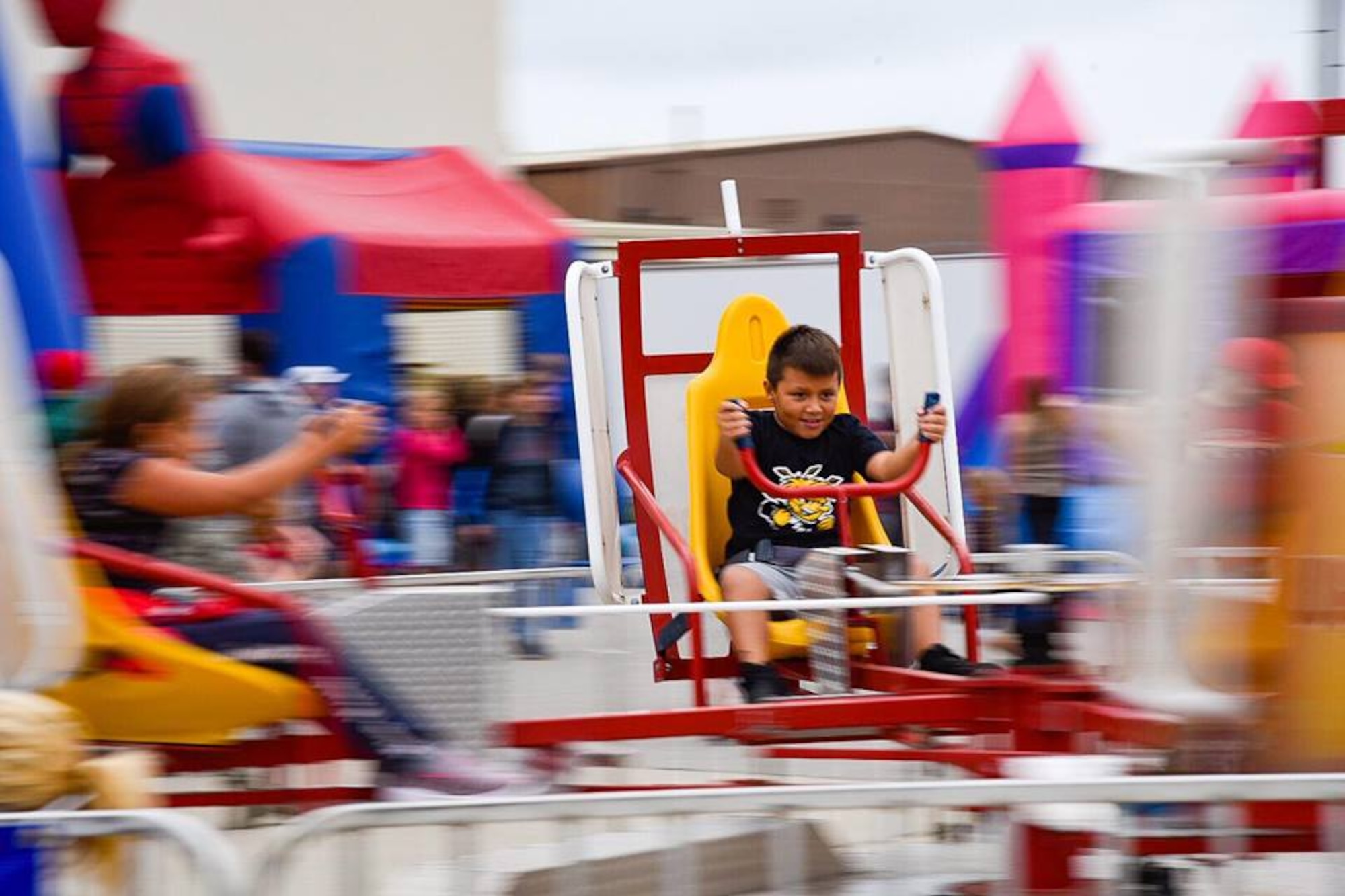 A child plays on a carnival ride at the Frontiers in Flight Open House and Air Show Sept. 8, 2018, at McConnell Air Force Base, Kansas. The show offered a “Kid Zone” where children could play while waiting for their favorite aerobatic performances. (U.S. Air Force photo by Airman 1st Class Michaela R. Slanchik)