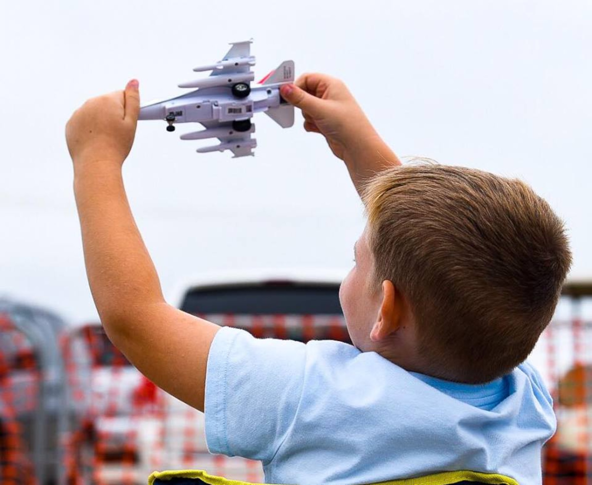 A child mocks aerial performances with a toy airplane during the Frontiers in Flight Open House and Air Show Sept. 8, 2018, at McConnell Air Force Base, Kansas. The event showcased aerobatic performances, static airplane displays, science, technology, engineering and match exhibits and a kids’ zone. (U.S. Air Force photo by Airman 1st Class Michaela R. Slanchik)