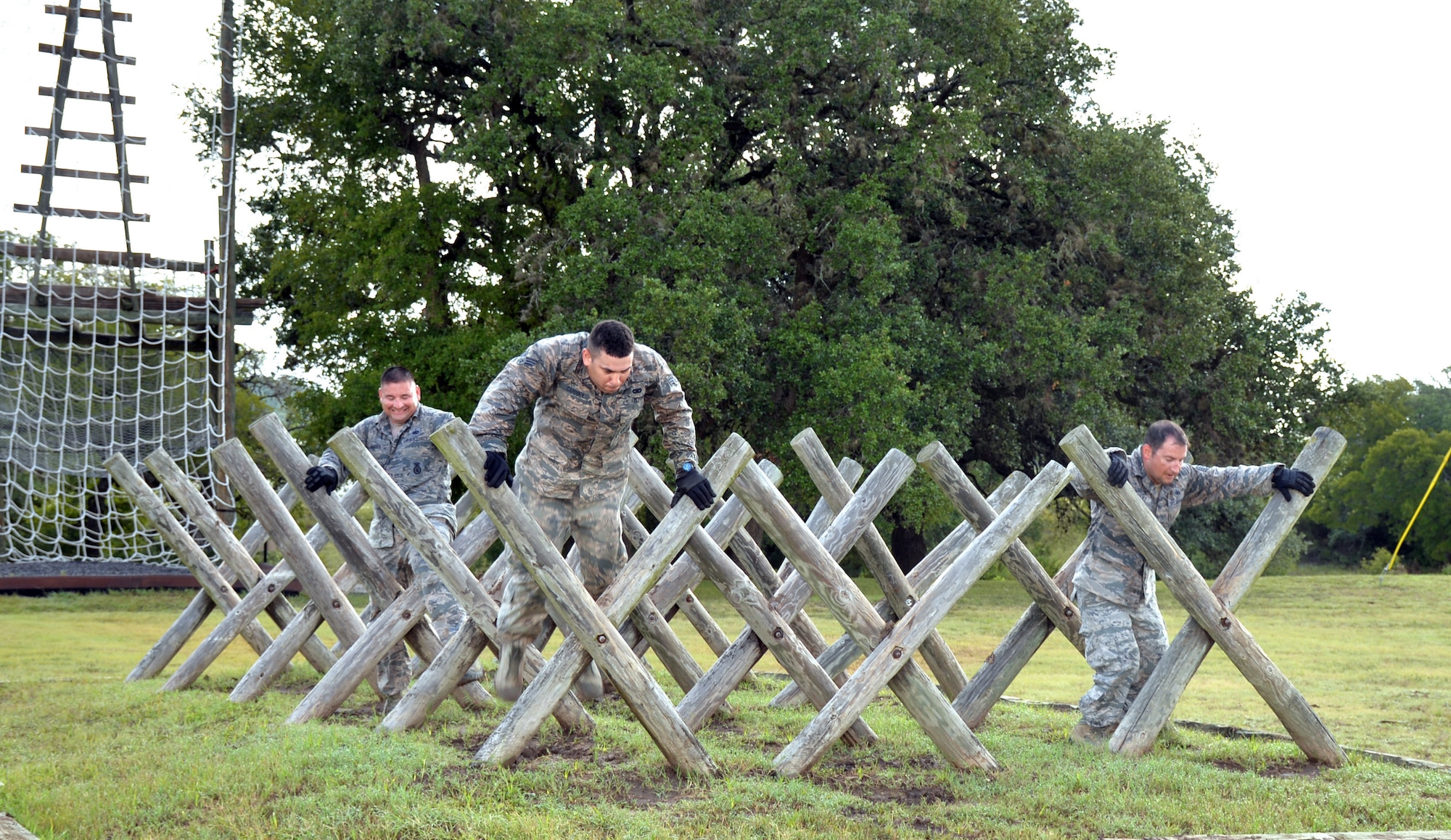 Air Force Reserve Command Defender Challenge Team Members Tech. Sgt. Mariano Flores, Senior Airman Rick Cardona, and Tech Sgt. Francisco Gonzalez, navigate the “Tough Nut” obstacle at the Camp Bullis Military Training Reservation, Texas, Sept. 6, 2018.