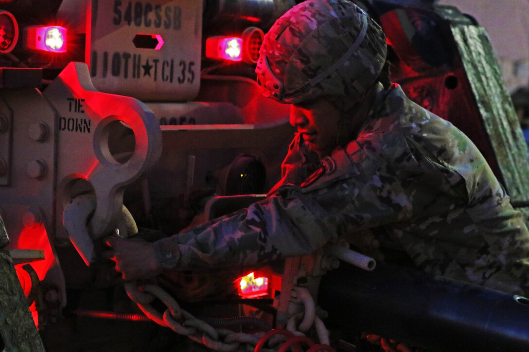 A soldier attaches a trailer to a vehicle.