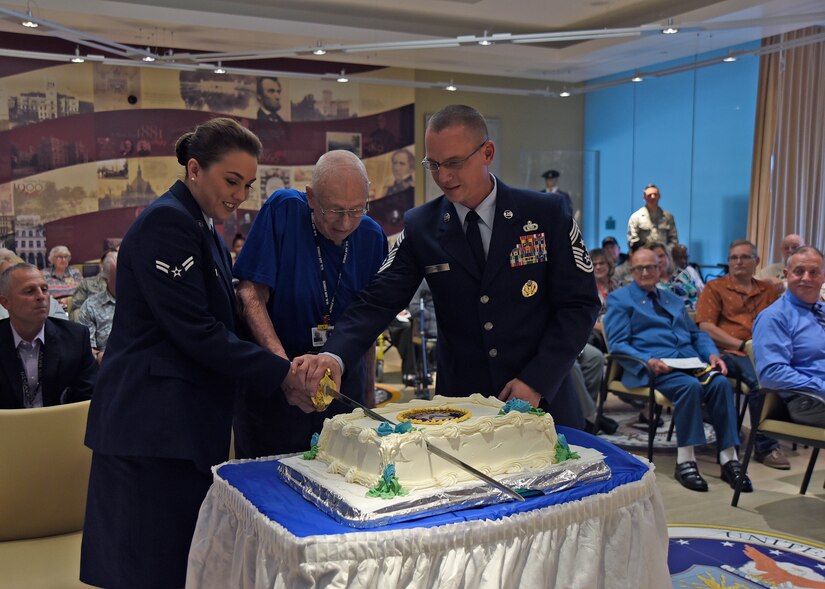 Chief Master Sgt. Thomas C. Daniels, 11th Wing and JBA command chief, retired Tech. Sgt. George Setzer, Armed Forces Retirement Home resident, and Airman 1st Class Skylar Armstrong, 1st Airlift Squadron flight attendant, cut a cake at the AFRH, D.C., Sept. 14, 2018. Joint Base Andrews Airmen joined retirees from the AFRH to celebrate the Air Force’s 71st birthday. (U.S. Air Force photo by Senior Airman Abby L. Richardson)