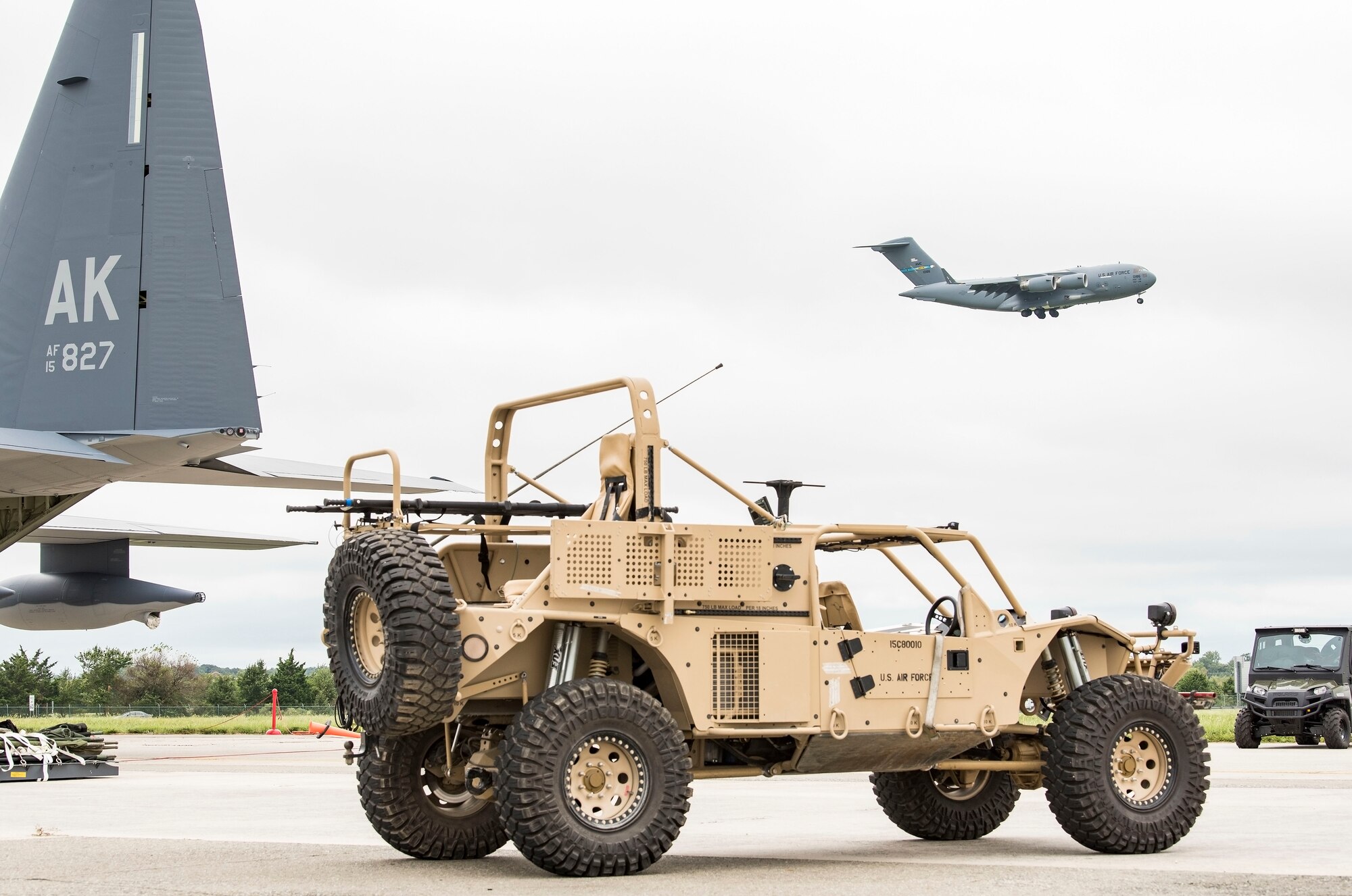 A Guardian Angel Air-droppable Rescue Vehicle assigned to the Alaska Air National Guard, 176th Wing, Joint Base Elmendorf-Richardson, Alaska, sits near the tail of a HC-130J while a C-17 Globemaster III flies in the background Sept. 13, 2018, at Dover Air Force Base, Del. Members and equipment from the 176th Wing, 176th Aircraft Maintenance Squadron, 211th and 212th Rescue Squadrons at JBER arrived at Dover on Sept. 12 to support hurricane relief efforts when called upon. (U.S. Air Force photo by Roland Balik)