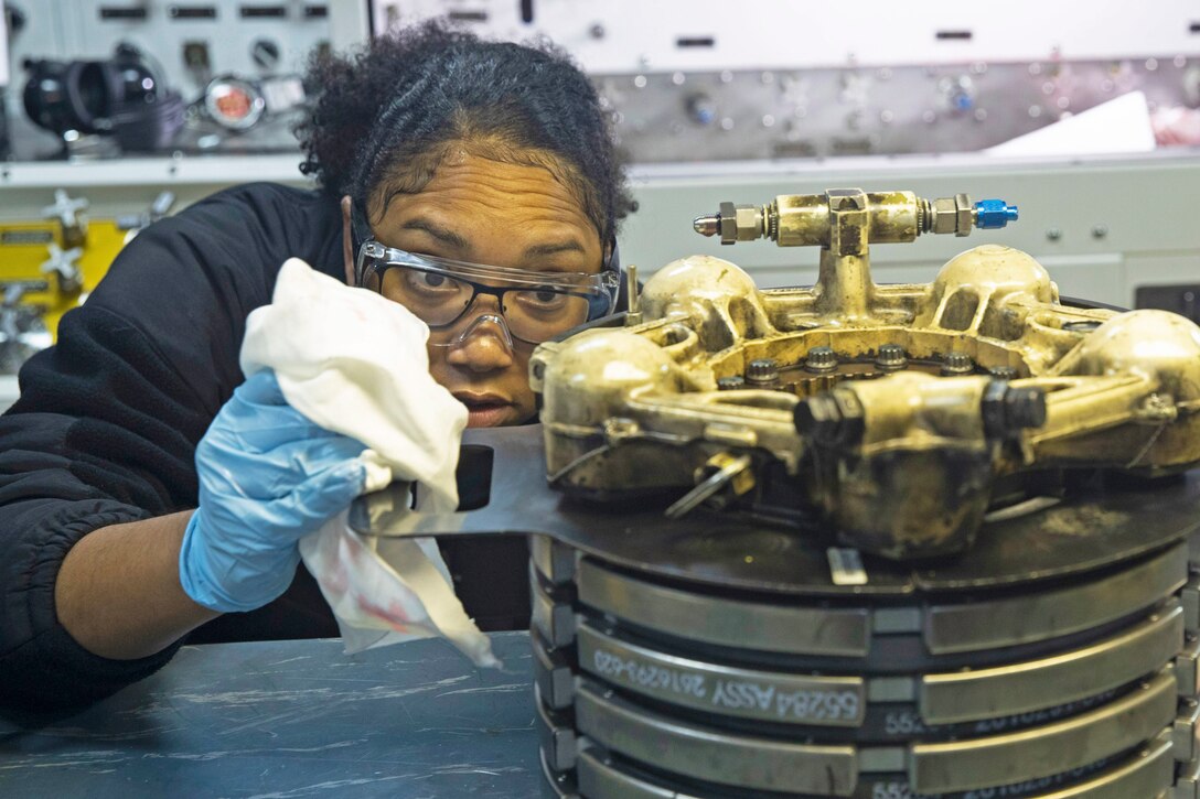 A sailor examines an aircraft brake.