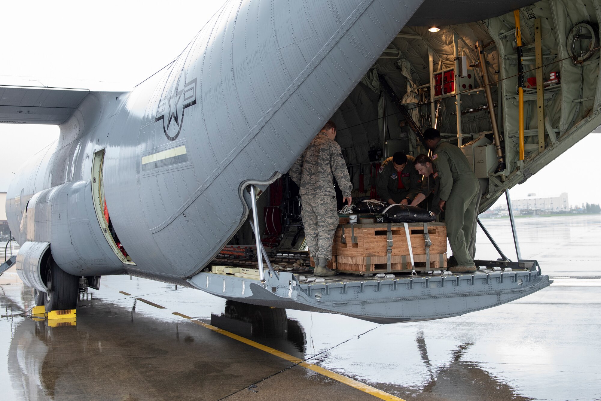 The loadmasters of a C-130J Super Hercules work with members of the 374th Logistics Readiness Squadron to secure a bundle to be dropped during a low-cost, low-altitude demonstration at the 2018 Japanese-American Friendship Festival at Yokota Air Base, Japan, Sept. 15, 2018.
