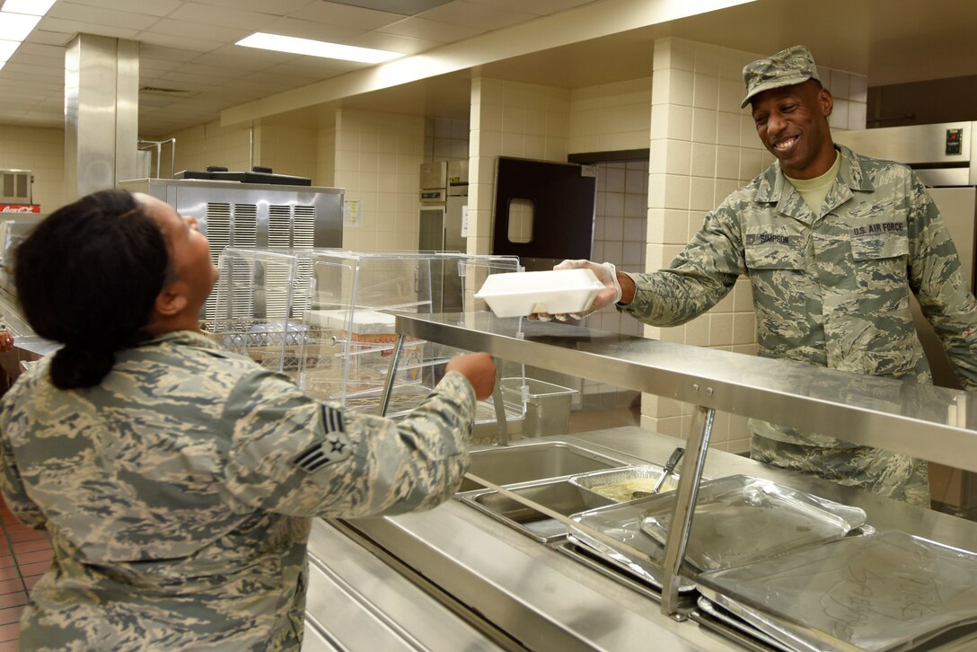 U.S. Air Force Senior Airman Tyron Simpson, 145th Force Support Squadron, hands a hot meal to Senior Airman Barbara Johnson, 145th Operations Group, early Friday morning, Sept. 14, 2018 in the dining facility during preparation for Hurricane Florence at the North Carolina Air National Guard Base, Charlotte Douglas International Airport. Airmen across the base prepare for power outages that may occur as a result of Hurricane Florence.
