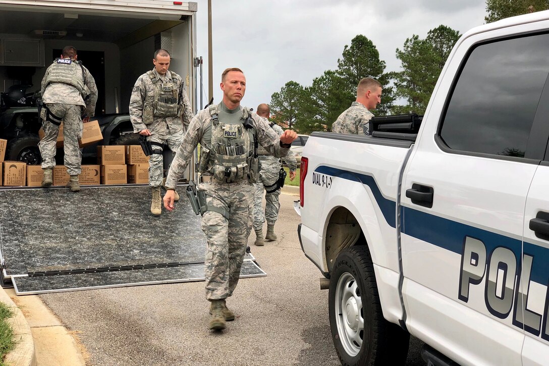 Airmen run to a police vehicle as they deploy to help search and rescue efforts following Hurricane Florence.