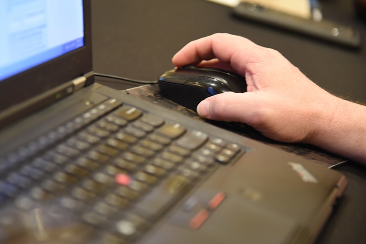 A Louisiana National Guardsman’s hand guides a mouse while studying IBM’s i2 Notebook.