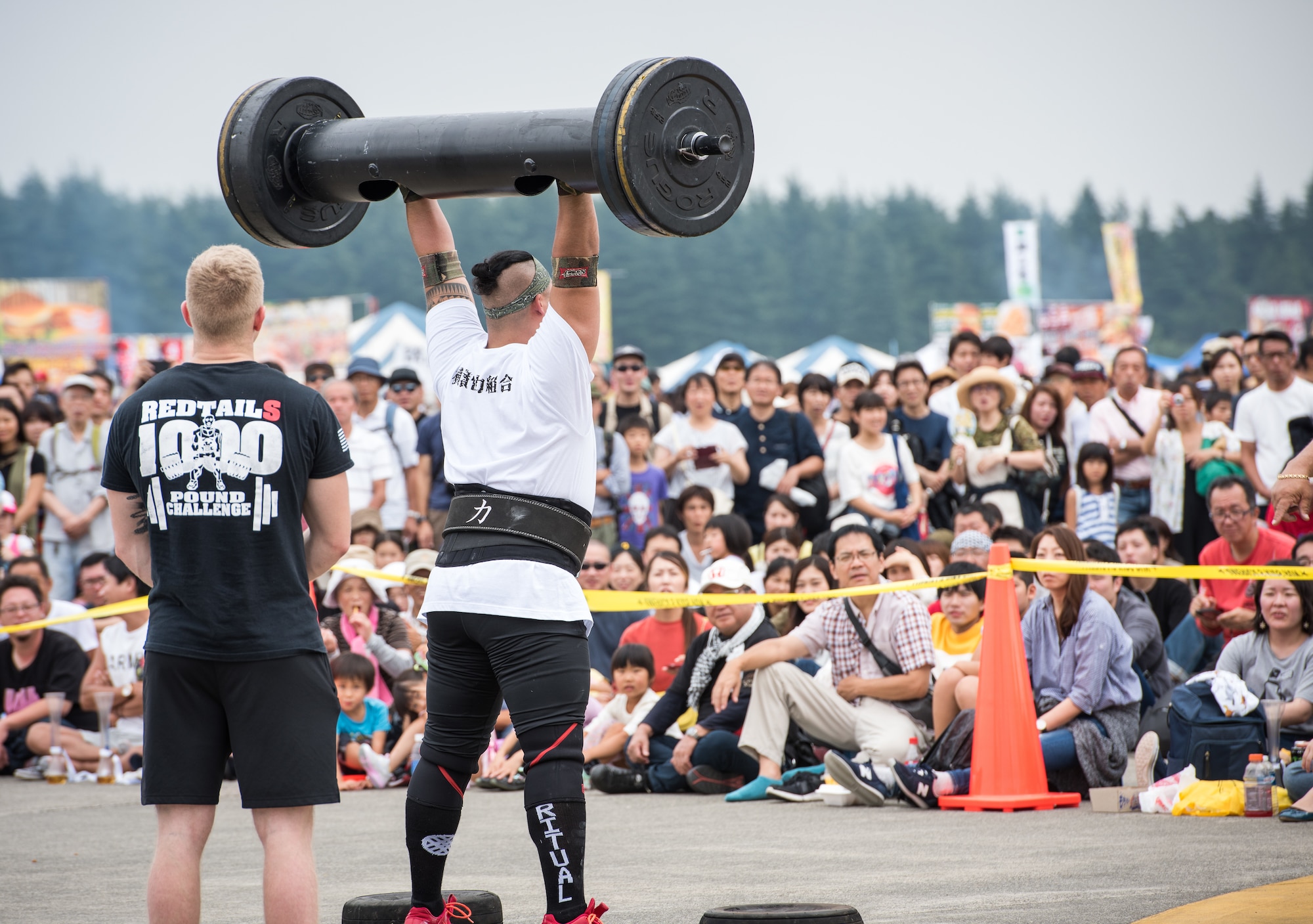 A Strongman Competition contestant performs a military press