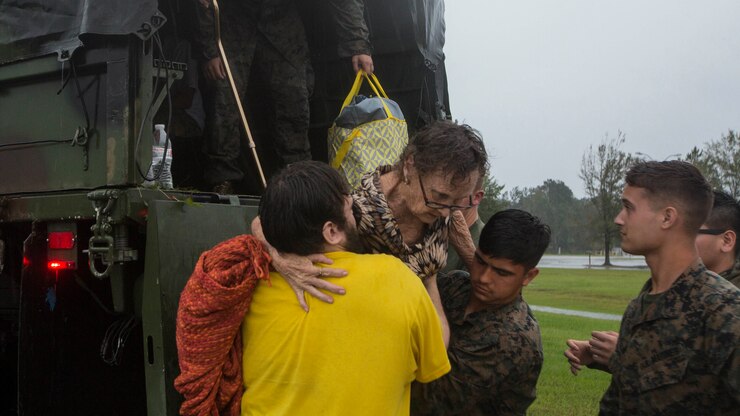 Marines help a resident get off the back of a military vehicle.