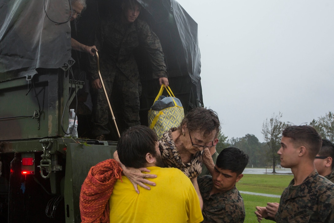 Marines help a resident get off the back of a military vehicle.