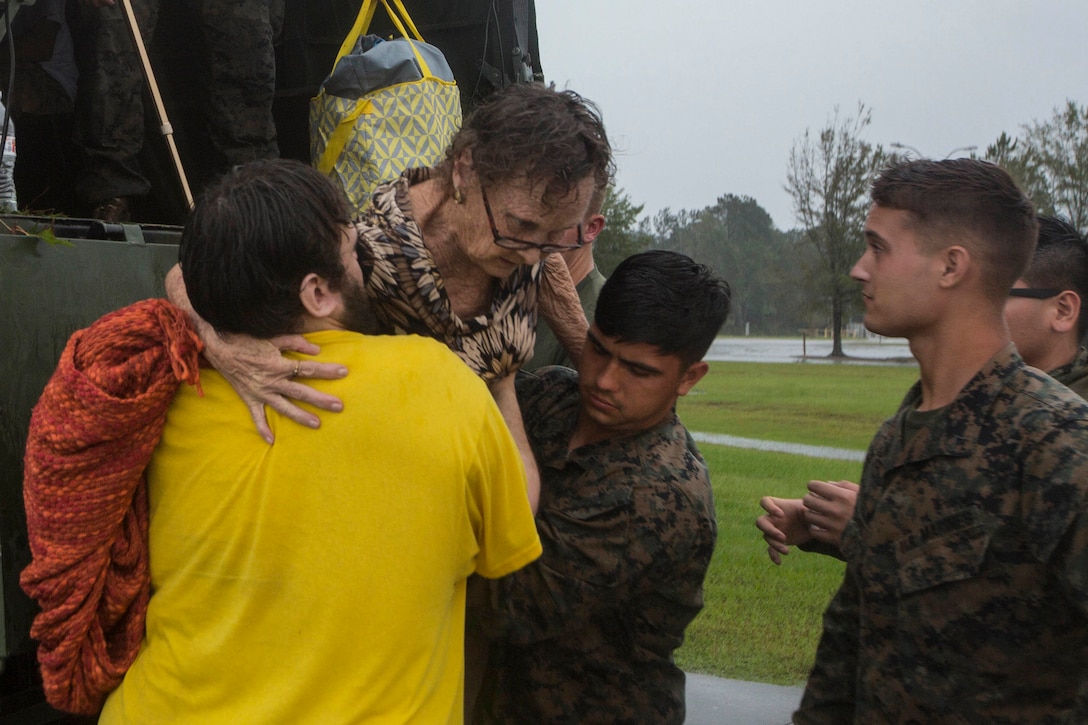 Marines help a resident get off the back of a military vehicle.