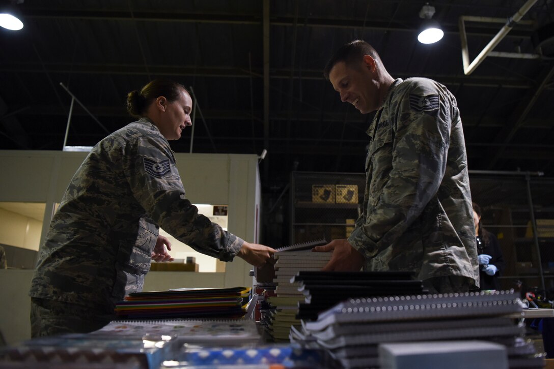 U.S. Air Force Tech. Sgt. Kayla Rosensteil (left), 8th Logistics Readiness Squadron flight service center noncommissioned officer in charge, and Tech. Sgt. Jeffrey Cook, 8th LRS individual protective equipment noncommissioned officer in charge, organize supplies collected from  a Back to School Drive at Kunsan Air Base, Republic of Korea, Sept. 13, 2018. Donations included notebooks, writing utensils, erasers, books, backpacks, and other supplies to give to local schools in the community. (U.S. Air Force photo by Senior Airman Savannah L. Waters)