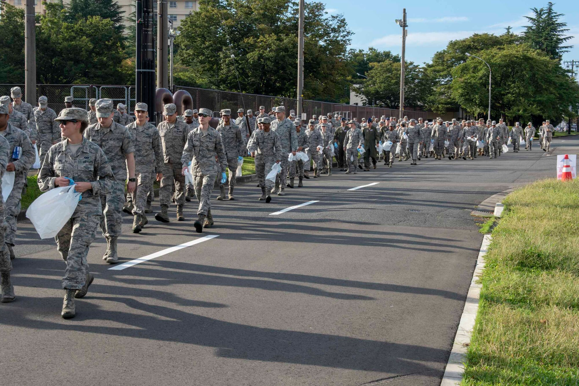 The Airmen of the 374th Airlift Wing walk to the flightline with bags and gloves in hand as part of the post 2018 Japanese-American Friendship Festival foreign object debris walk at Yokota Air Base, Sept. 17, 2018.