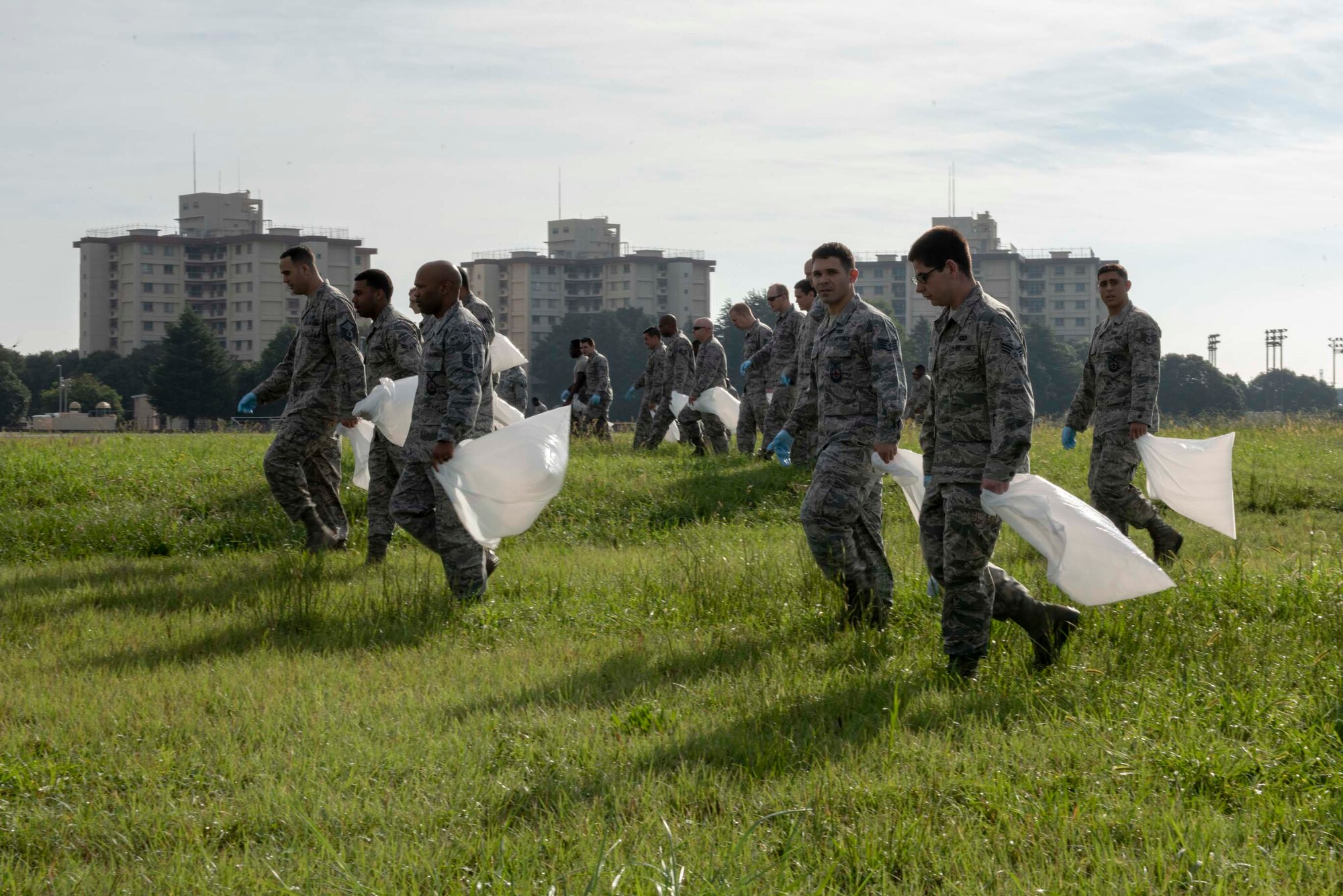 The Airmen of the 374th Airlift Wing search the flightline with bags and gloves in hand as part of the post 2018 Japanese-American Friendship Festival foreign object debris walk at Yokota Air Base, Sept. 17, 2018.