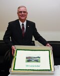 Ron R. Rahorn, the department head of the Broadcast Operations and Maintenance Department at the Defense Information School on Fort George G. Meade, Maryland poses in front of his commemorative cake Aug. 30 following his retirement ceremony. (U.S. Navy photo by Navy Seaman Apprentice Jarrod A. Schad)