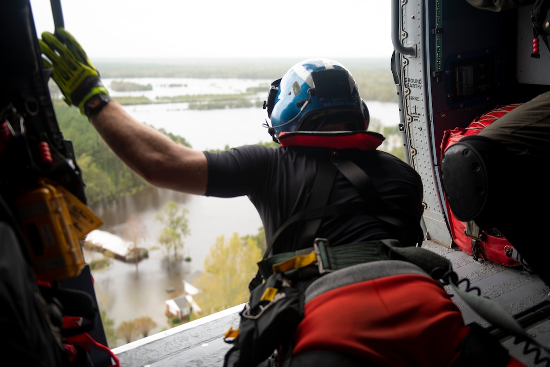 A member of the Coast Guard looks out from a helicopter over the severe flooding in North Carolina.