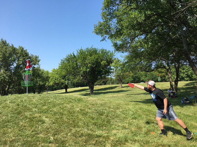 A disc golfer lets go toward the basket.