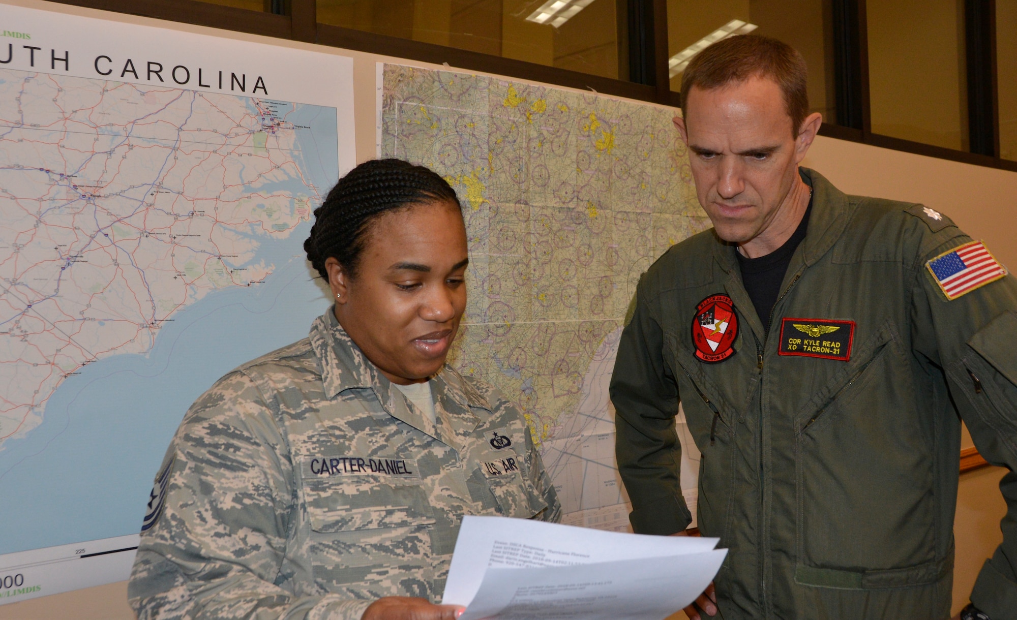 Tech.  Sgt. Theresa Carter-Daniels, Air Forces Northern Search and Rescue Operation Coordination Element controller, reviews information about potential search and rescue operations for Hurricane Florence with U.S. Navy CDR. Kyle Read, AFNORTH SAR OCE Naval Liaison Element. Total Force representation during AFNORTH’s Defense Support of Civil Authorities efforts includes active-duty U.S. Navy, U.S. Marine Corps, U.S. Army, U.S. Coast Guard, and U.S. Air Force, Guard, Reservists and civilians. (Air Force photo by Mary McHale)