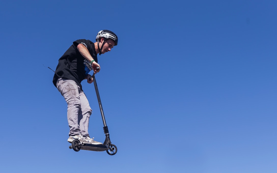 Bransyn Smith, professional Razor Scooter rider and X-Games athlete, performs a tail whip off of a box jump during the X-Games Action Sports Show at the Marine Corps Exchange parking lot aboard the Marine Corps Air Ground Combat Center, Twentynine Palms, Calif., Sept. 8, 2018. The X-Games provided a social recreational event in honor of the continuous service and sacrifice military personnel and family members make for the country. (U.S. Marine Corps photo by Pfc. Robin Lewis)