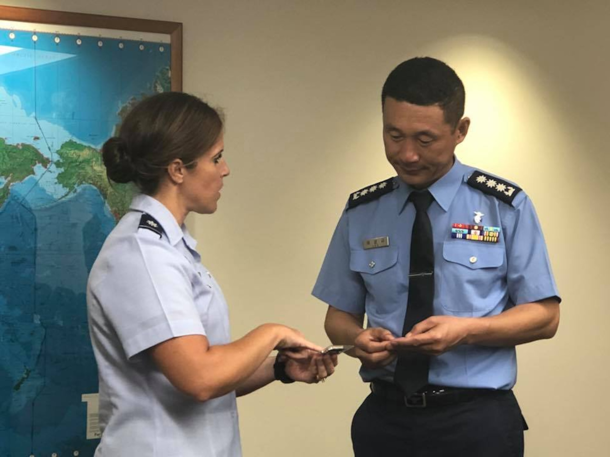 U.S. Air Force Lt. Col. Meagan Schafer exchanges a Pacific Air Forces Public Affairs coin with Republic of Korea Air Force Col. Sang-ky Lee after a meeting aimed at facilitating relationships and dialogue between ROKAF/PA and their U.S. counterparts at Joint Base Pearl Harbor-Hickam, Hawaii Sept. 11, 2018. During the meeting, Lee, also met with professionals from the PACAF/PA, PACAF Band, PACAF Historian, Indo-pacific Command, 7th AF, and the Korean International Affairs Liaison and discussed future ways to engage on the Korean Peninsula. (U.S. Air Force photo by Master Sgt. Nadine Y. Barclay)