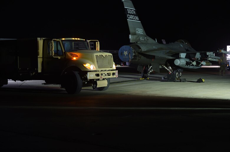 A fuel truck pumps gas to a jet at might time