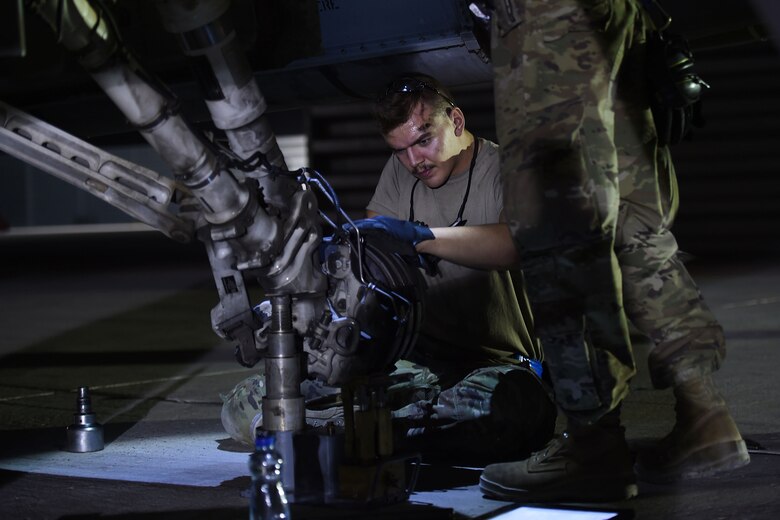 An Airman changes a tire on a jet
