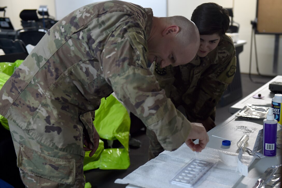 An airman uses a dropper to drop liquid into a test kit