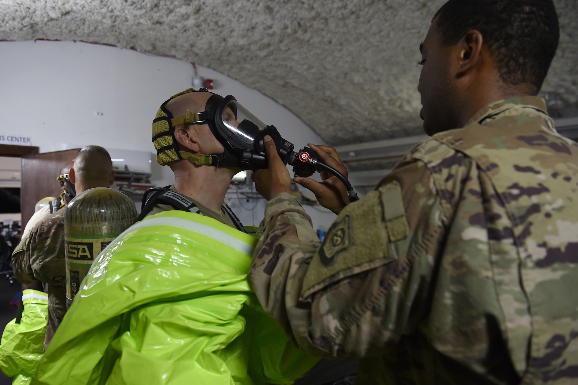 An Airman helps another Airman put on SCBA mask