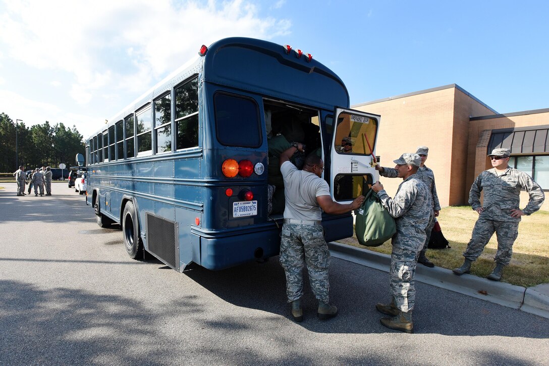 Airmen load their gear and equipment onto a bus preparing to deploy.