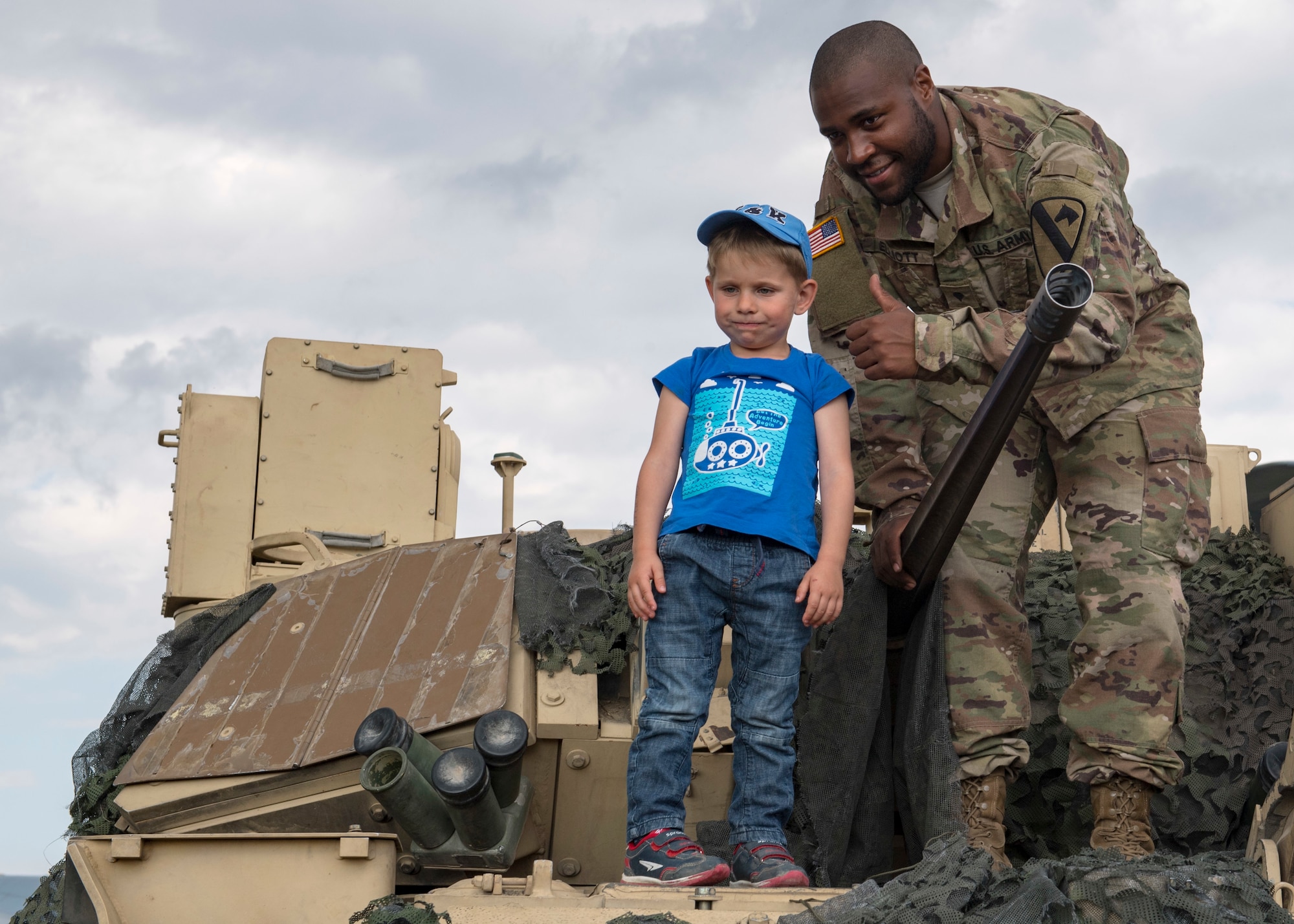 Specialist James Elliott, assigned to Bravo Company, 2-12th Cavalry Regiment, poses for a photo with an air show attendee on top of a Bradley Fighting Vehicle at Ostrava Air Base, Czech Republic, during NATO Days. NATO Days is a Czech Republic-led air show and exhibition that showcases military ground and aviation capabilities from 19 nations. Participation in NATO Days increases our understanding of European ally and partner capabilities, greatly enhancing our ability to operate together as a team. (U.S. Navy photo by Mass Communication Specialist 2nd Class Robert J. Baldock)