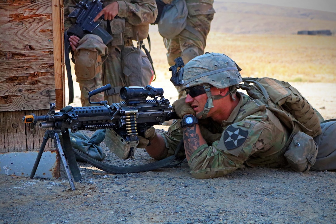 A soldier takes aim with his machine gun while providing security on a live-fire range.