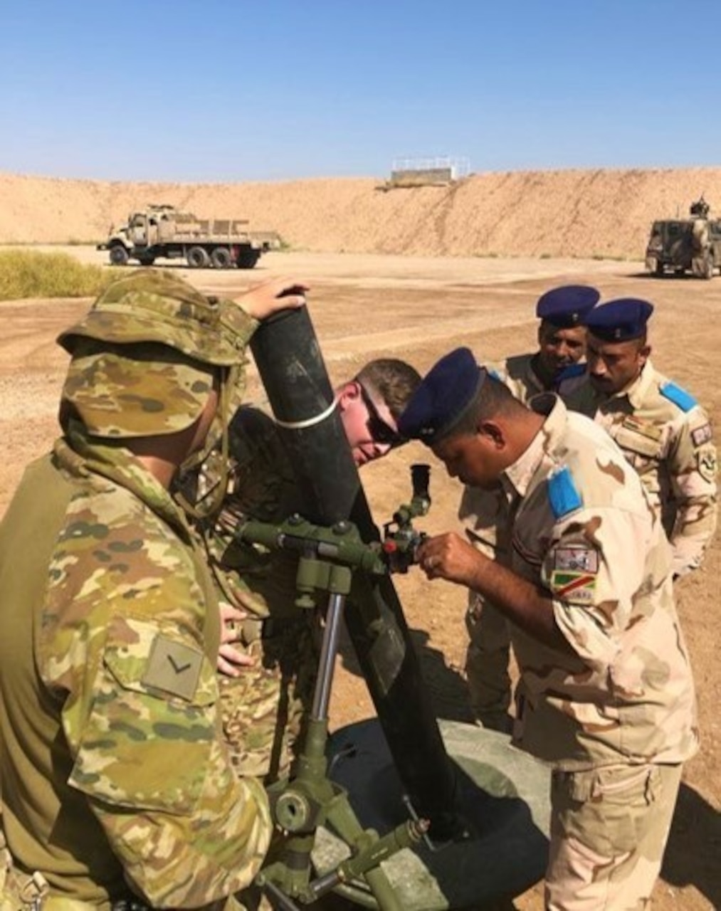 U.S. and Australian army instructors show an Iraqi soldier an M120 mortar system.