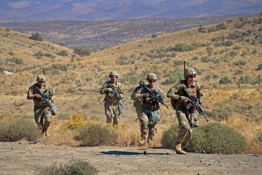 Soldiers rush forward toward their follow-on objective on a live-fire range.
