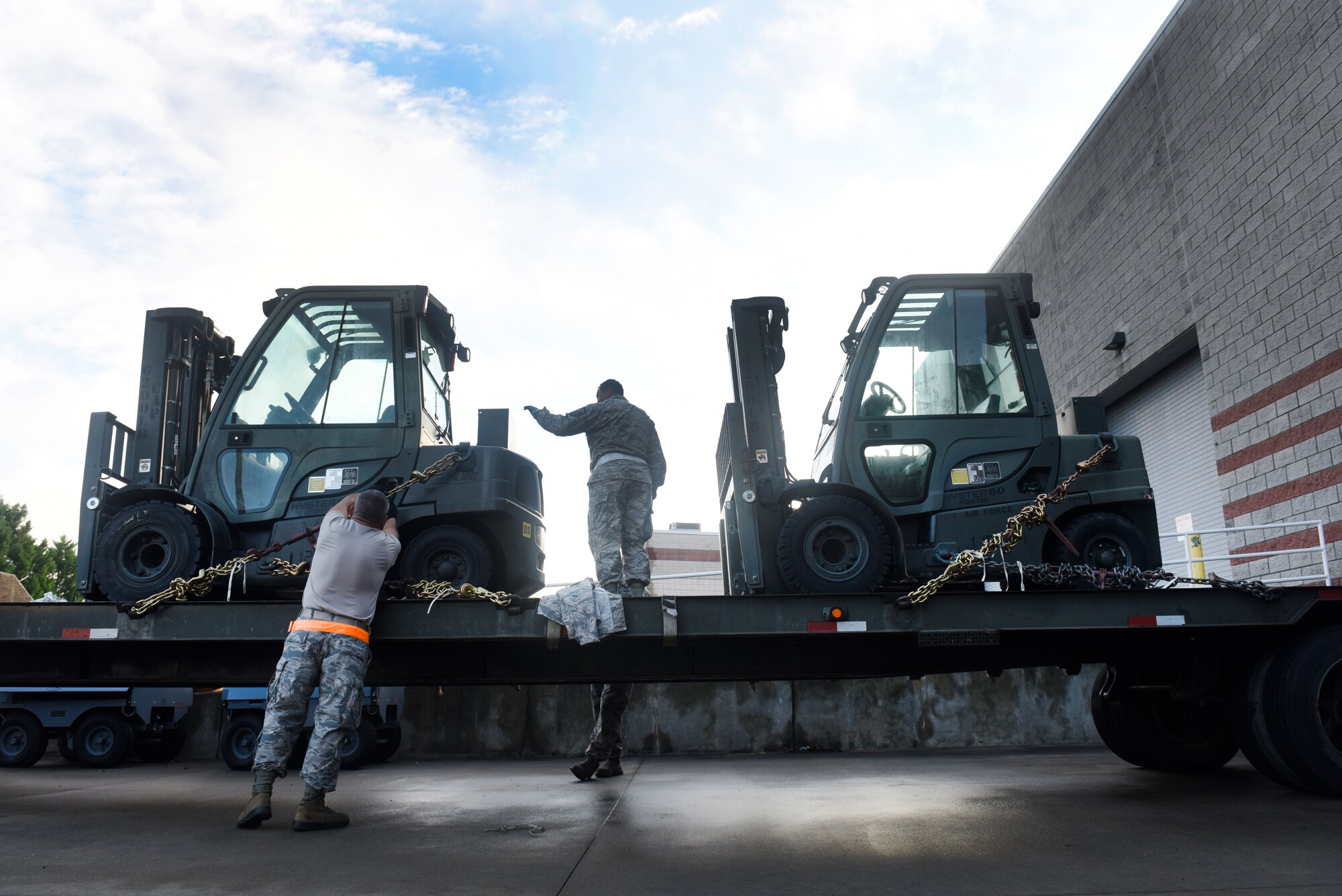 U.S. Air Force Senior Master Sgt. Raymond Graves III (left) and Master Sgt. Barry Boyd (middle), 145th Logistics Readiness Squadron, chain down two forklifts to a flatbed truck at the North Carolina (N.C.) Air National Guard Base, Charlotte Douglas International Airport, Sept.17, 2018.  The forklifts will be used to move pallets filled with supplies like food and water in an attempt to assist in relief efforts associated with Hurricane Florence, and will be transported with an 11-person team to an airport in Kinston, N.C.