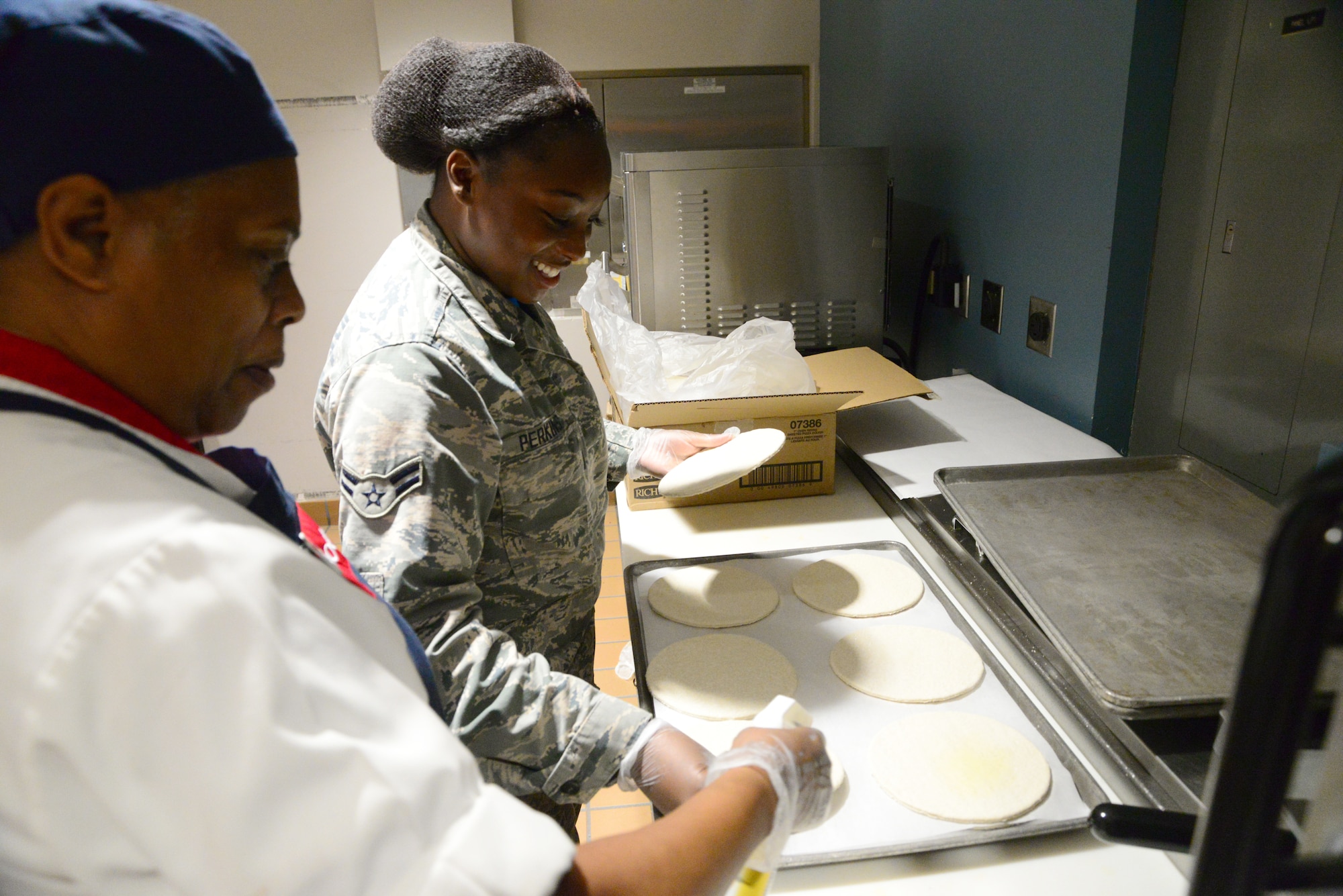 Pam Marshall (left), line cook, and Airman 1st Class Tayion Perkins, 436th Force Support Squadron food service apprentice, begin preparing pizza’s for the lunch time rush Sept. 14, 2018, at the Patterson Dining Facility on Dover Air Force Base, Del. The combined efforts of Airmen and civilians improve the dining experience for DFAC customers. (U.S. Air Force photo by Airman 1st Class Dedan Dials)