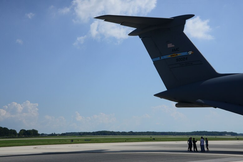 Marine Corps System Command land systems defense acquisition engineers and logisiticans stand under the tail of a C-5M Super Galaxy Sept 5, 2018, at Dover Air Force Base, Del. Last year members from MARCORSYSCOM land systems defense acquisition team came to Dover AFB to see how an MQ-9 Reaper is loaded onto an aircraft. (U.S. Air Force photo by Airman First Class Jonathan Harding)