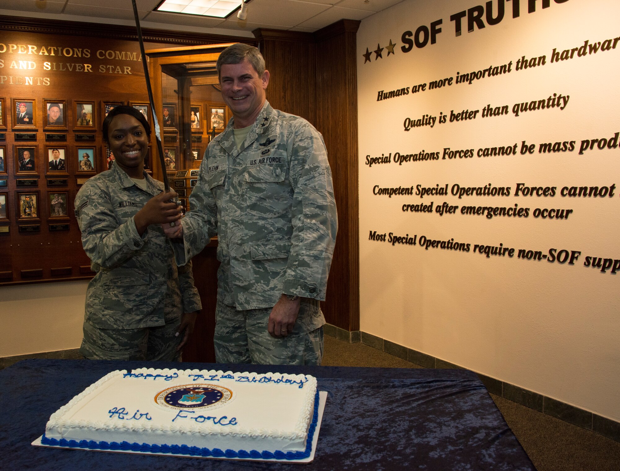 Two people in front of a cake on a table.